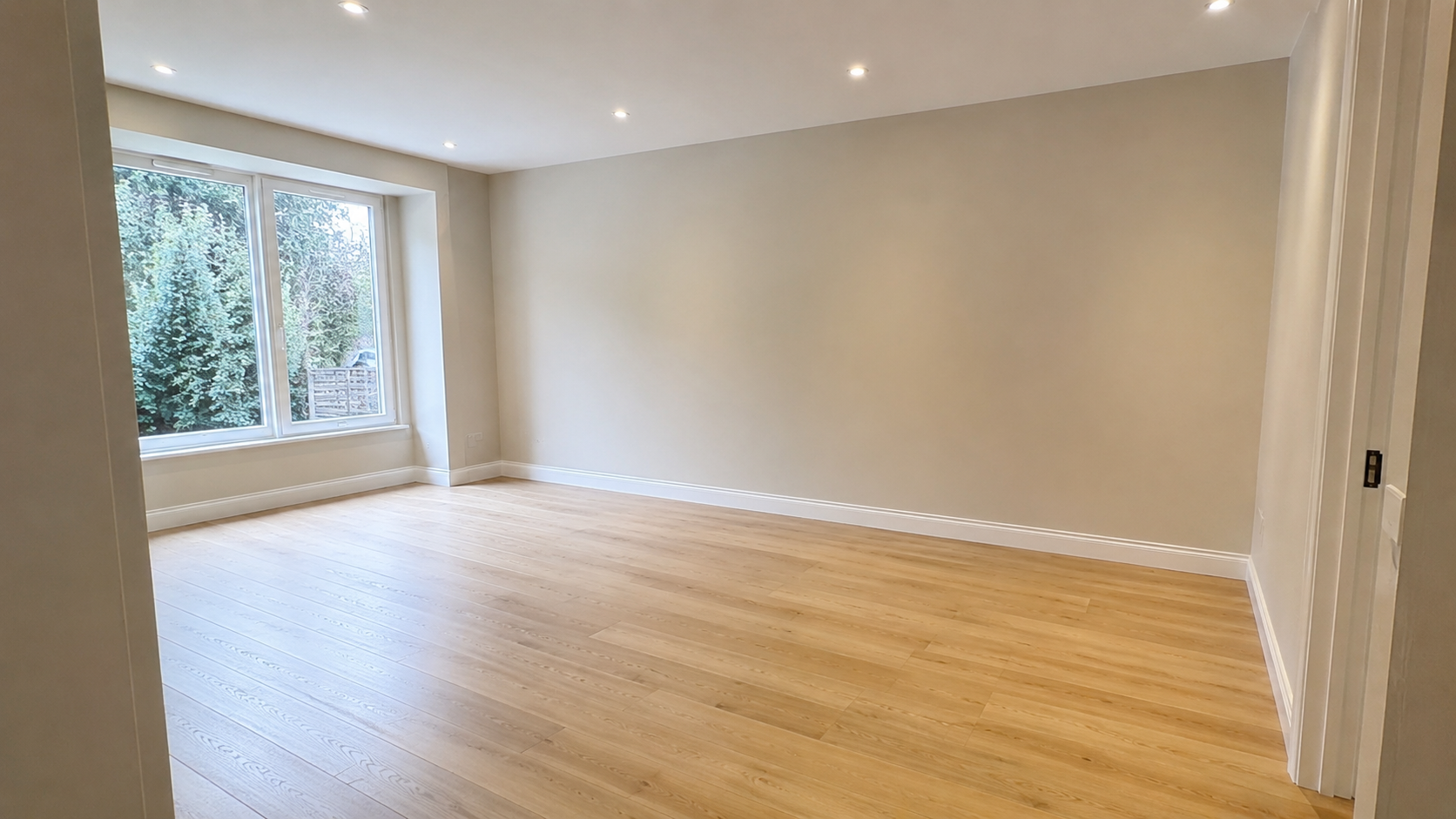 Pièce rénovée avec parquet clair et vue sur jardin